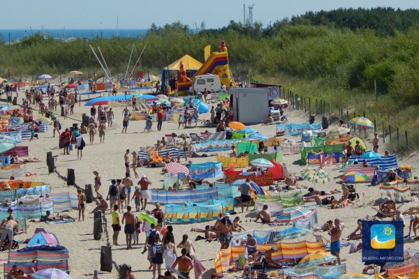 Piaszczysta plaża, zaś w tle coś dla najmłodszych - dmuchana zjeżdżalnia.